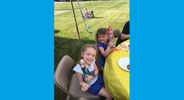 Two girls playing with dolls at a picnic